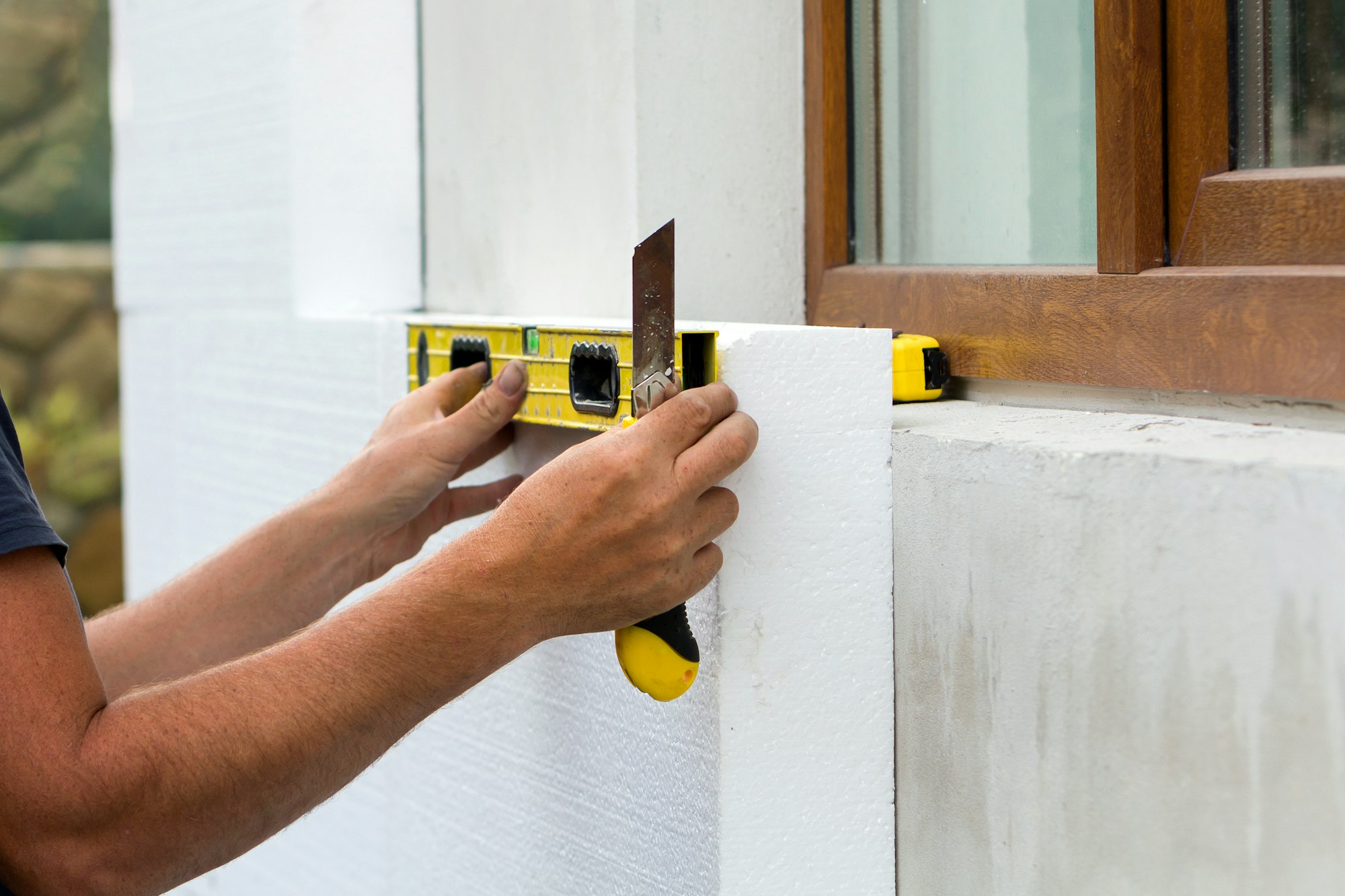 Construction worker insulating house wall with styrofoam insulatuion sheet
